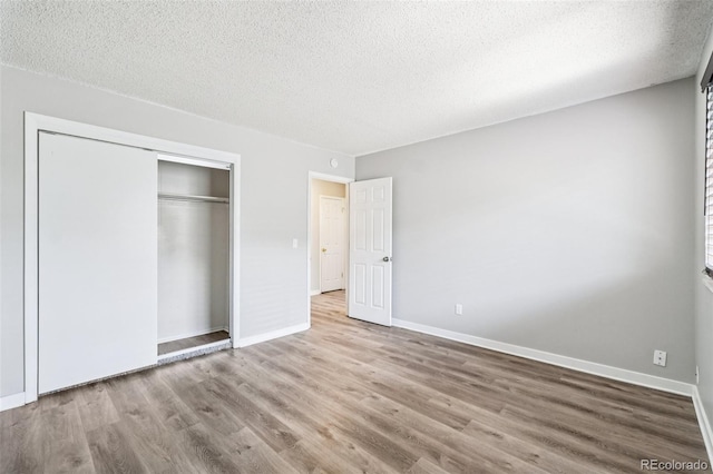 14590 E 13th Ave, Aurora, CO 80011 - unfurnished bedroom featuring wood finished floors, a textured ceiling, and a closet