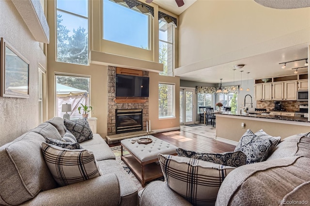 9743 Chanteclair Cir, Highlands Ranch, CO 80126 - living area featuring healthy amount of natural light, hardwood / wood-style flooring, a high ceiling, a stone fireplace, and ceiling fan