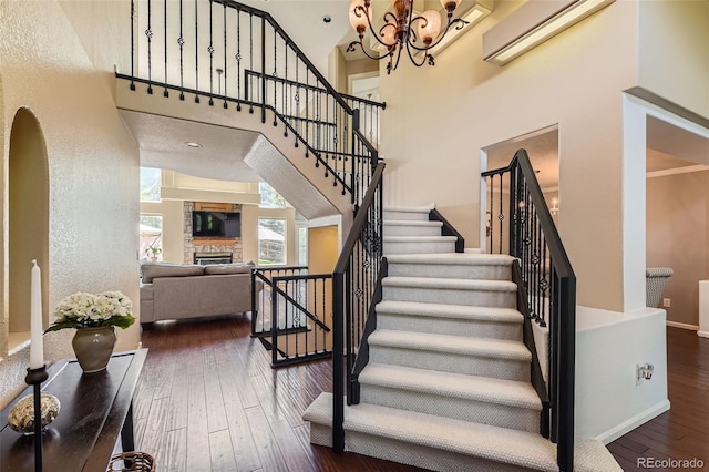 9743 Chanteclair Cir, Highlands Ranch, CO 80126 - staircase featuring a wall mounted AC, a fireplace, a chandelier, wood-type flooring, and a high ceiling