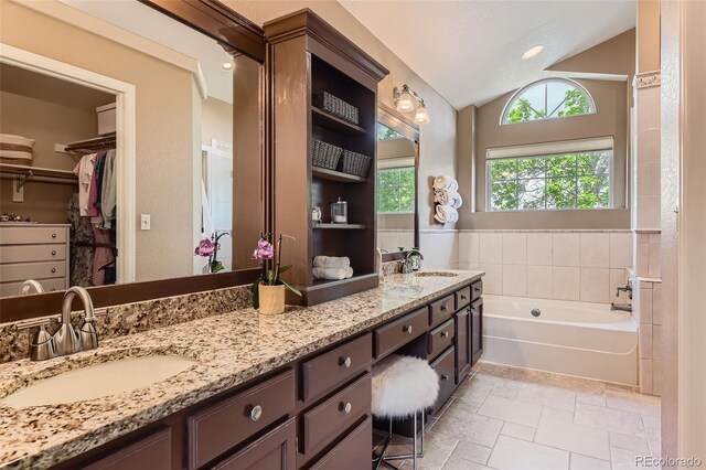 9743 Chanteclair Cir, Highlands Ranch, CO 80126 - full bath with double vanity, lofted ceiling, a garden tub, a spacious closet, and stone tile floors
