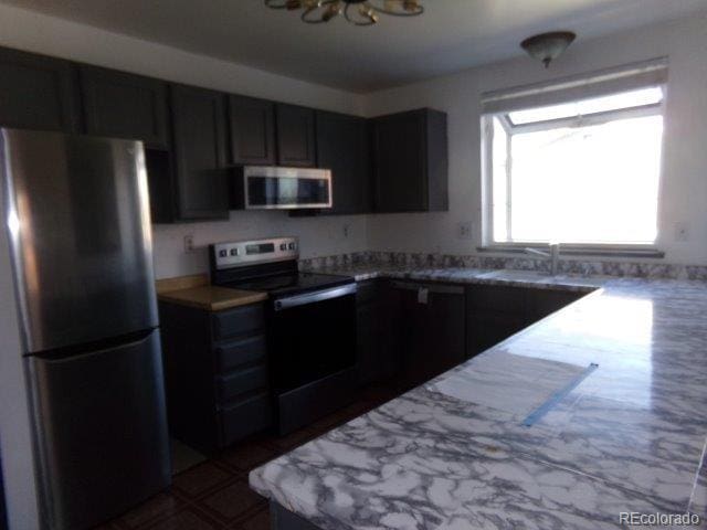 1889 S Flanders Way, Aurora, CO 80017 - kitchen featuring appliances with stainless steel finishes, light countertops, a chandelier, and dark cabinets