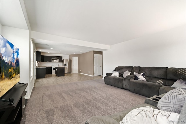 living area featuring baseboards, light wood-type flooring, recessed lighting, and light colored carpet