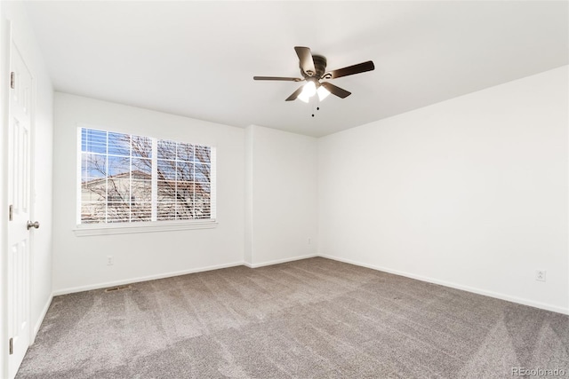 carpeted spare room featuring a ceiling fan and baseboards