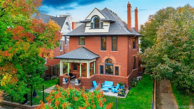 2155 N High St, Denver, CO 80205 - rear view of house with a chimney, a patio area, a shingled roof, and brick siding