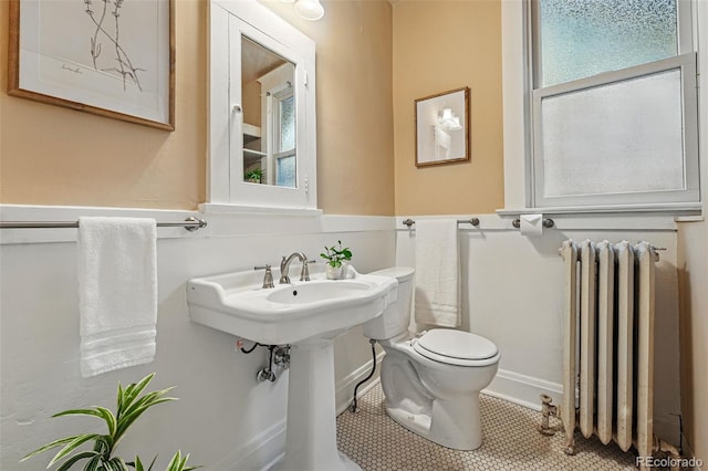 618 Adams St, Denver, CO 80206 - half bath with radiator heating unit, toilet, healthy amount of natural light, and tile patterned flooring