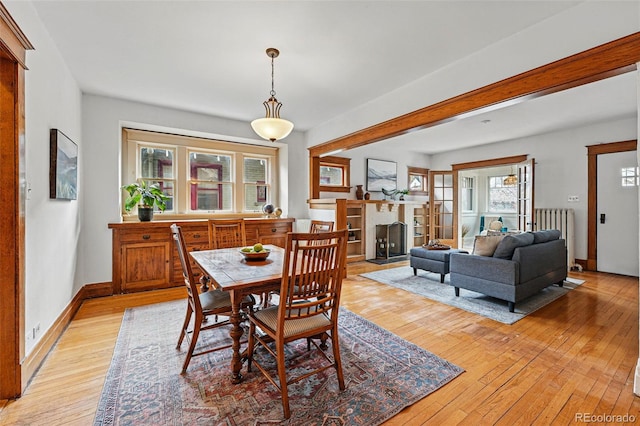 618 Adams St, Denver, CO 80206 - dining room featuring light wood-style flooring, radiator heating unit, a fireplace with flush hearth, baseboards, and beamed ceiling