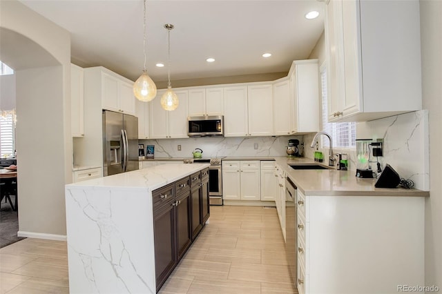 kitchen featuring a sink, stainless steel appliances, white cabinetry, decorative backsplash, and a kitchen island