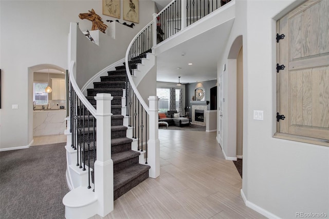 5830 Jasper Pointe Cir, Castle Pines, CO 80108 - foyer with arched walkways, stairs, a towering ceiling, baseboards, and a fireplace