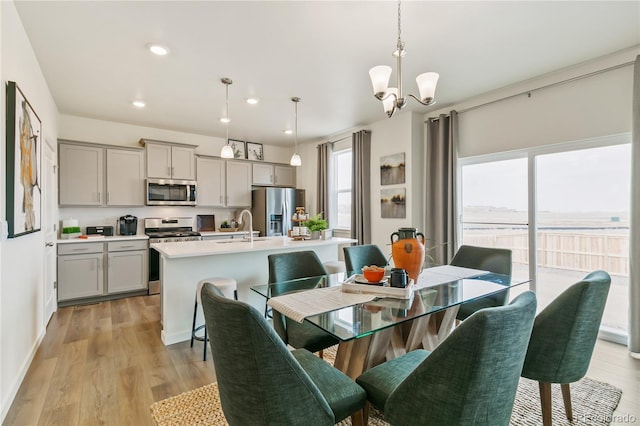 dining space with sink, a chandelier, and light wood-type flooring