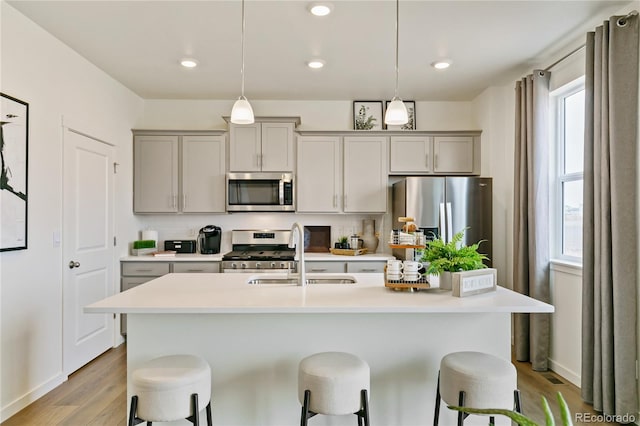 kitchen featuring gray cabinetry, hanging light fixtures, decorative backsplash, and stainless steel appliances