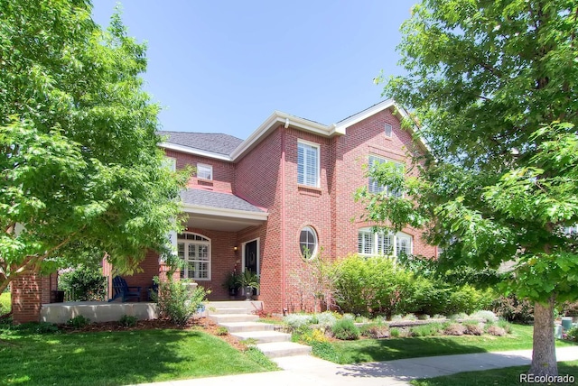 7527 E Severn Pl, Denver, CO 80230 - view of front of house featuring a front yard, brick siding, roof with shingles, and a porch
