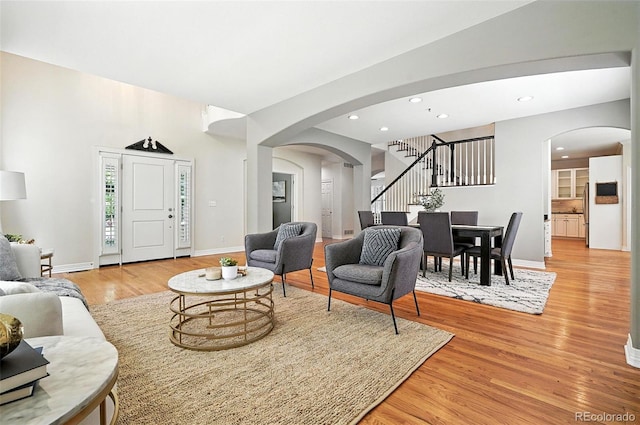 7527 E Severn Pl, Denver, CO 80230 - living room featuring arched walkways, stairway, light wood-type flooring, and recessed lighting