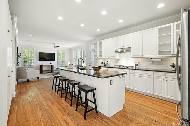 7527 E Severn Pl, Denver, CO 80230 - kitchen featuring stainless steel appliances, open floor plan, under cabinet range hood, light wood finished floors, and plenty of natural light