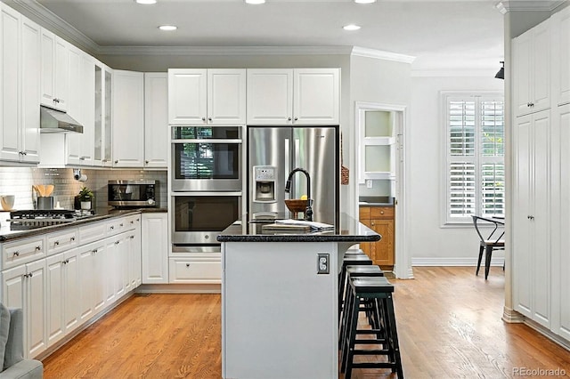 7527 E Severn Pl, Denver, CO 80230 - kitchen with stainless steel appliances, a breakfast bar area, crown molding, white cabinets, and recessed lighting