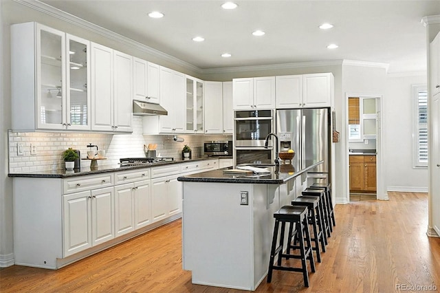 7527 E Severn Pl, Denver, CO 80230 - kitchen with ornamental molding, appliances with stainless steel finishes, a kitchen breakfast bar, tasteful backsplash, and white cabinetry