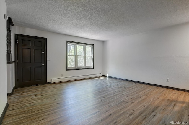 spare room featuring a baseboard heating unit, a textured ceiling, wood finished floors, and baseboards