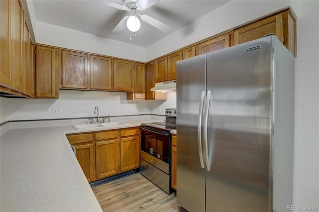 kitchen featuring range with electric cooktop, freestanding refrigerator, light countertops, under cabinet range hood, and a sink