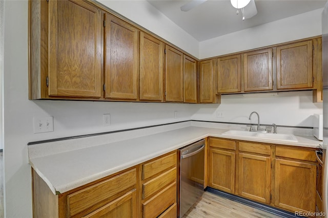 kitchen with brown cabinetry, light wood-style flooring, light countertops, stainless steel dishwasher, and a sink