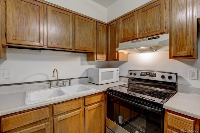 kitchen featuring light countertops, white microwave, stainless steel range with electric cooktop, a sink, and under cabinet range hood