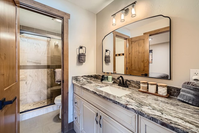 bathroom with vanity, a shower with door, and toilet