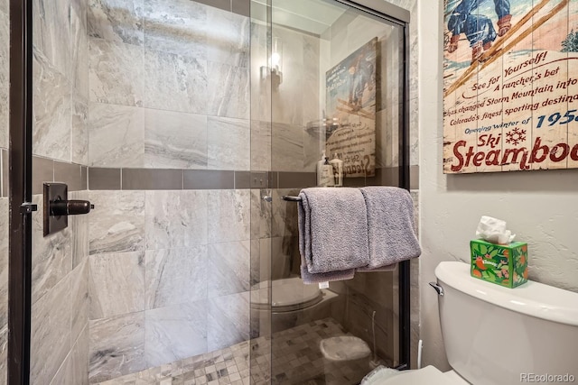 bathroom featuring a shower with door and toilet