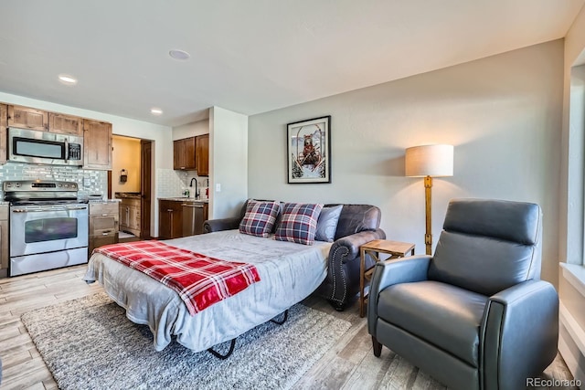 bedroom featuring connected bathroom, sink, and light hardwood / wood-style floors