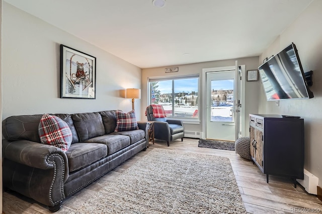 living room with a baseboard heating unit and light hardwood / wood-style floors