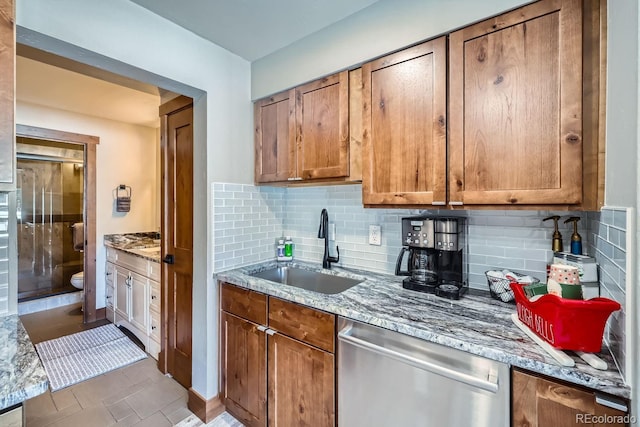 kitchen with tasteful backsplash, dishwasher, light stone countertops, and sink