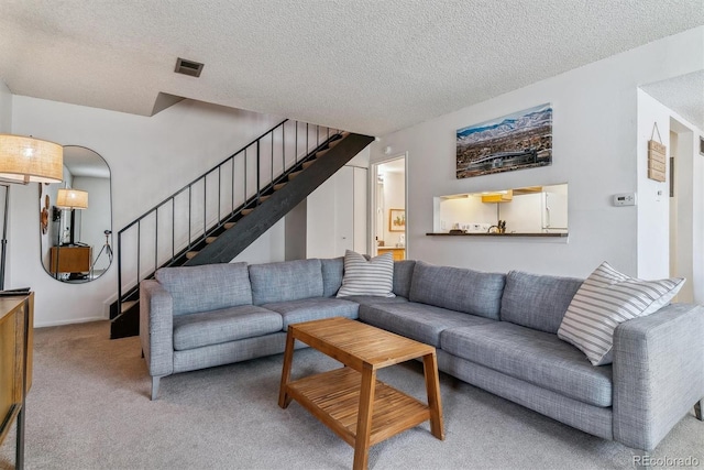 living area featuring light colored carpet, visible vents, a textured ceiling, and stairs