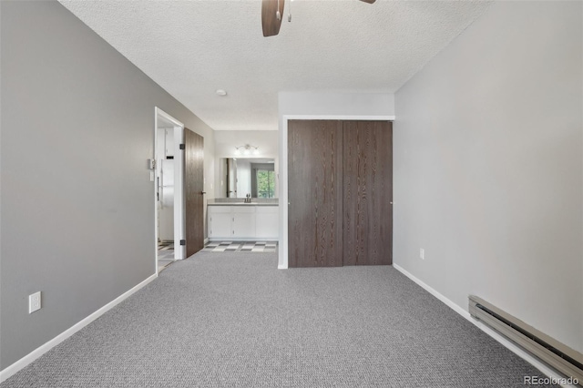 1118 City Park Ave Unit 226, Fort Collins, CO 80521 - unfurnished bedroom with a baseboard radiator, a textured ceiling, carpet floors, baseboards, and ensuite bath