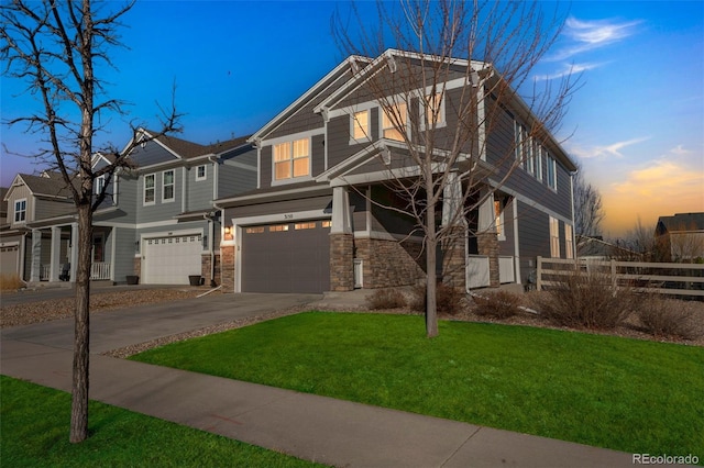 view of front of house featuring an attached garage, fence, a yard, stone siding, and driveway