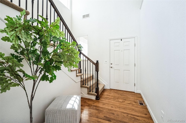 entryway with visible vents, a high ceiling, baseboards, and wood finished floors