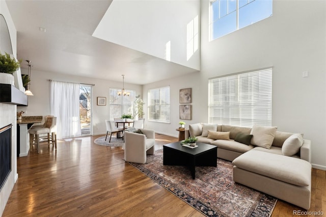 living area featuring a fireplace, wood finished floors, baseboards, and a chandelier