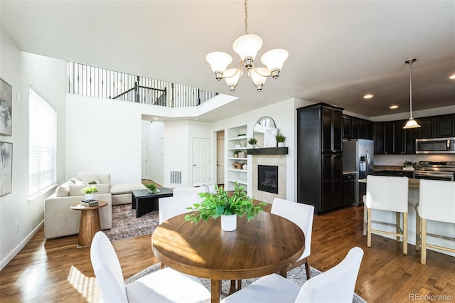 dining area with built in shelves, visible vents, dark wood finished floors, a fireplace, and a notable chandelier