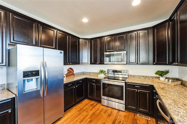 kitchen featuring light stone counters, visible vents, light wood finished floors, recessed lighting, and appliances with stainless steel finishes