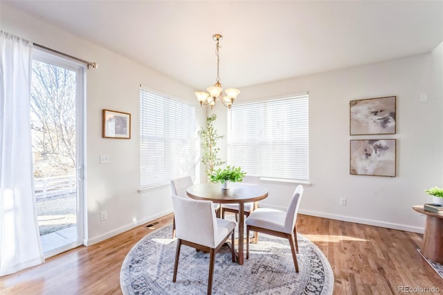 dining space with a notable chandelier, light wood-type flooring, and baseboards