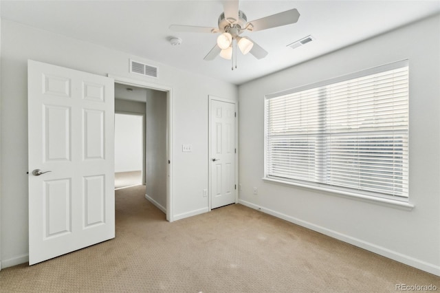 unfurnished bedroom with a ceiling fan, light colored carpet, visible vents, and baseboards