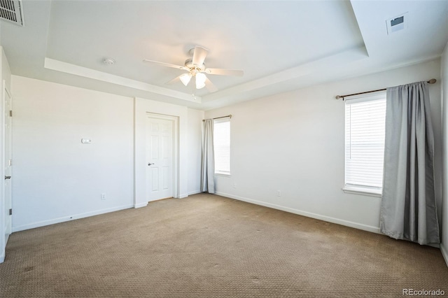 unfurnished room featuring visible vents, ceiling fan, baseboards, carpet, and a tray ceiling