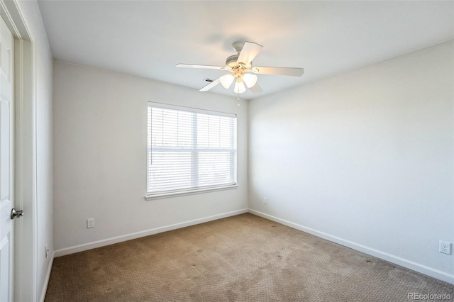 carpeted spare room featuring a ceiling fan and baseboards