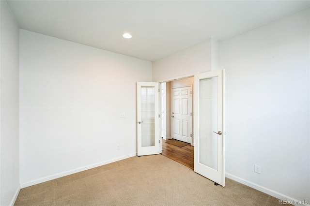 unfurnished bedroom featuring light carpet, recessed lighting, french doors, and baseboards