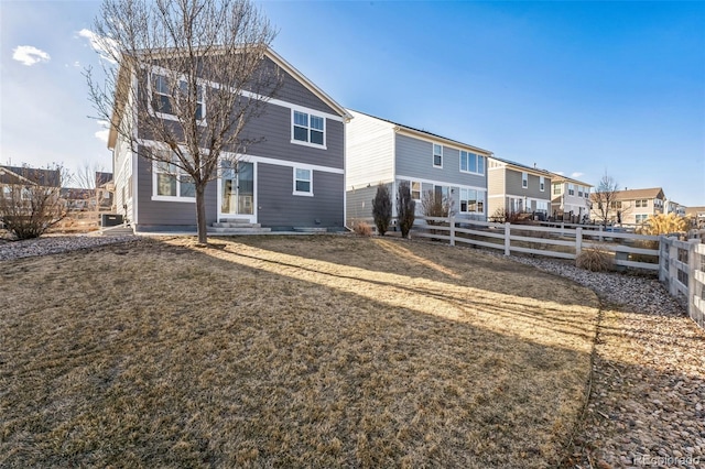 back of house featuring entry steps, a yard, fence, and a residential view