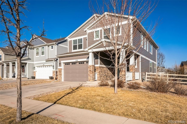 craftsman-style house with an attached garage, fence, stone siding, and driveway