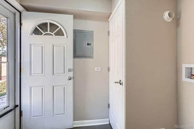 foyer entrance with electric panel and baseboards