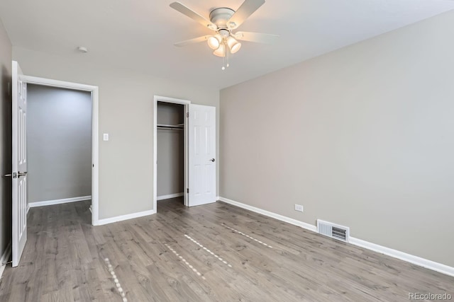 unfurnished bedroom with visible vents, wood finished floors, a closet, baseboards, and ceiling fan