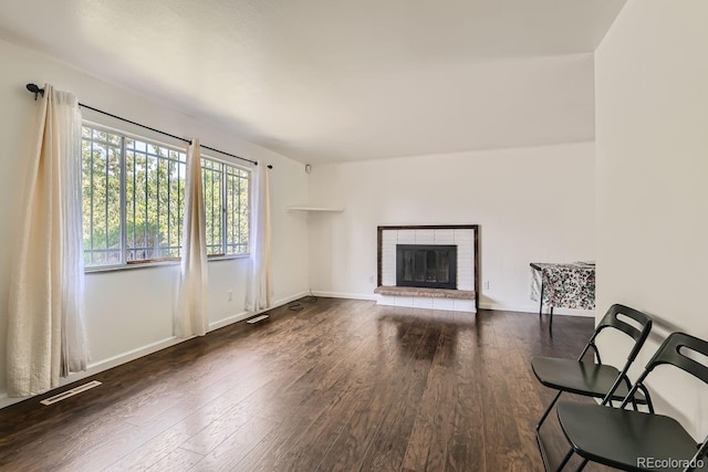 unfurnished living room featuring a brick fireplace, wood finished floors, visible vents, and baseboards