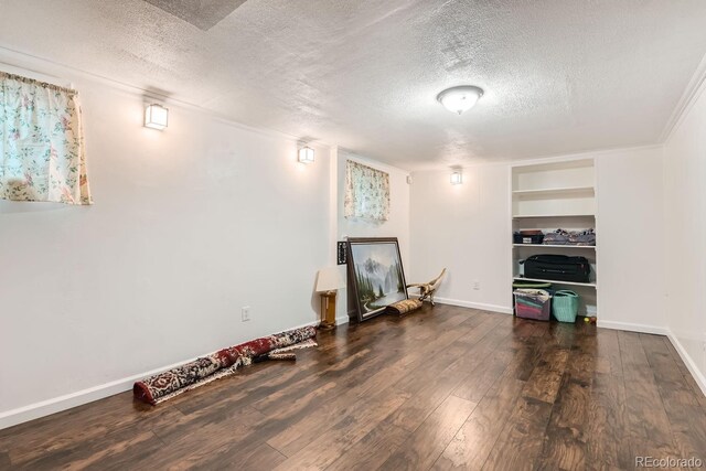 unfurnished living room featuring dark hardwood / wood-style floors, built in shelves, and a textured ceiling