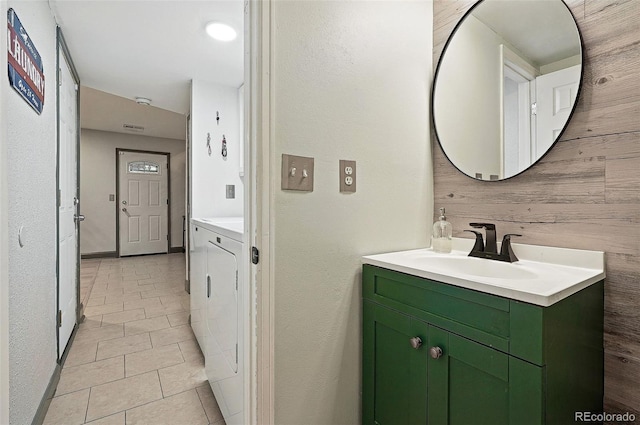 15034 E Floyd Ave, Aurora, CO 80014 - bathroom featuring vanity, separate washer and dryer, tile patterned flooring, and wooden walls