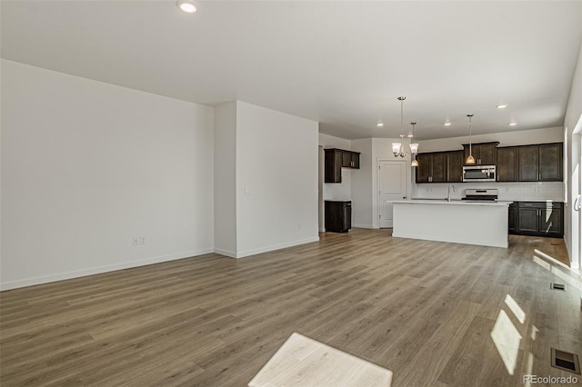 unfurnished living room with an inviting chandelier, light hardwood / wood-style floors, and sink