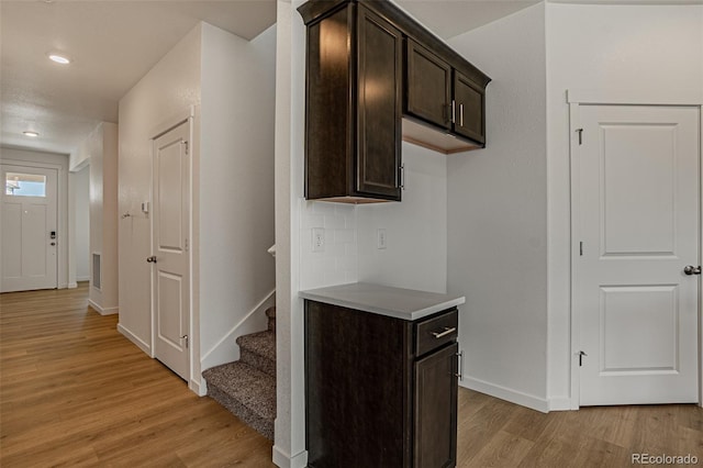 kitchen featuring light hardwood / wood-style flooring, dark brown cabinetry, and tasteful backsplash