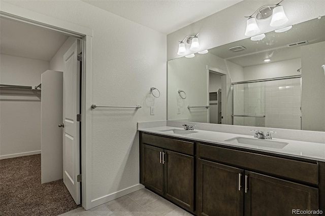 bathroom featuring tile patterned flooring, an enclosed shower, and vanity